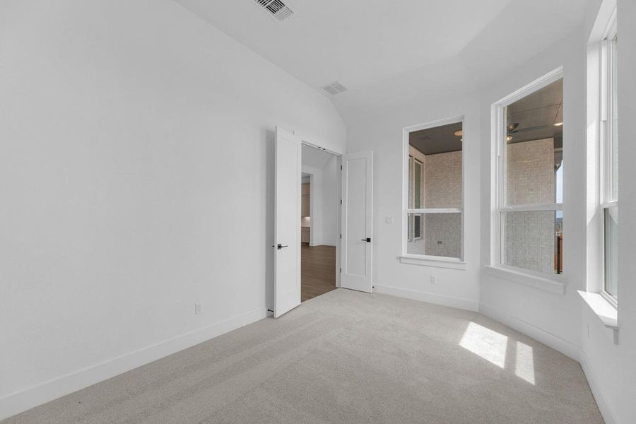 Carpeted empty room with baseboards and vaulted ceiling Carpeted empty room with baseboards and vaulted ceiling