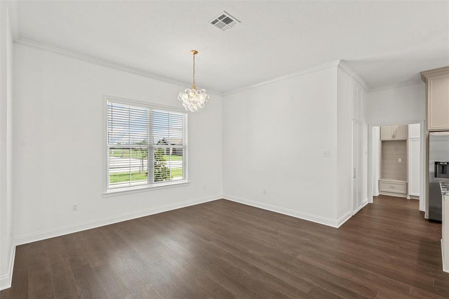 Spare room featuring a chandelier, dark wood-type flooring, and ornamental molding Spare room featuring a chandelier, dark wood-type flooring, and ornamental molding
