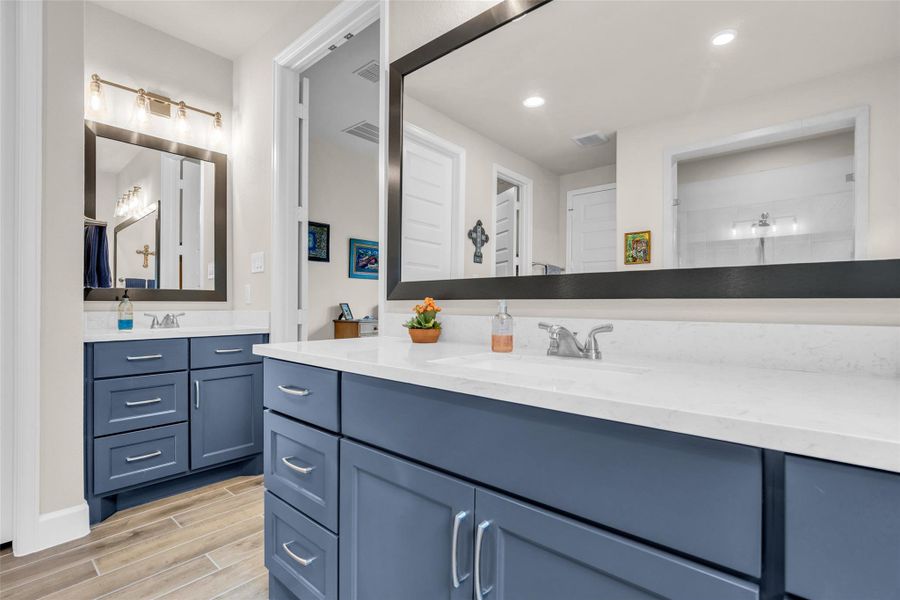 Separate, dual vanities and gorgeous blue cabinetry highlight the primary bathroom. Separate, dual vanities and gorgeous blue cabinetry highlight the primary bathroom.