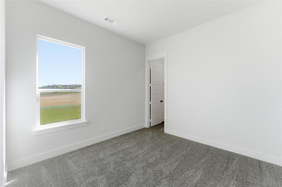 Spare room featuring dark carpet and baseboards