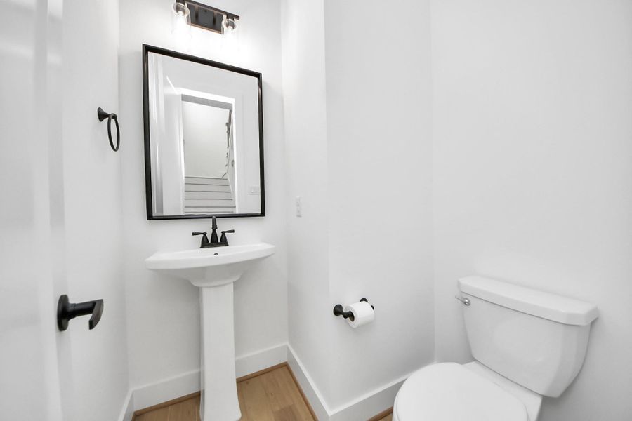 Your modern half-bathroom comes completed with custom paint, featuring a pedestal sink, and a modern framed black matte mirror with overhead lighting. A window allows for rays natural lighting. Your modern half-bathroom comes completed with custom paint, featuring a pedestal sink, and a modern framed black matte mirror with overhead lighting. A window allows for rays natural lighting.