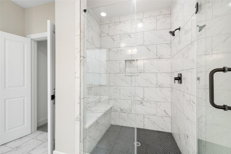 The spacious, modern shower is a true standout, featuring sleek glass doors and elegant white marble tiles. With dual shower heads, a built-in bench, and recessed shelving for added convenience, this shower offers both luxury and functionality.