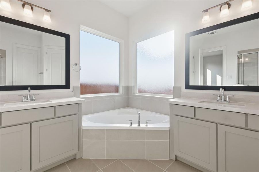 Full bathroom featuring a stall shower, two vanities, and a garden tub