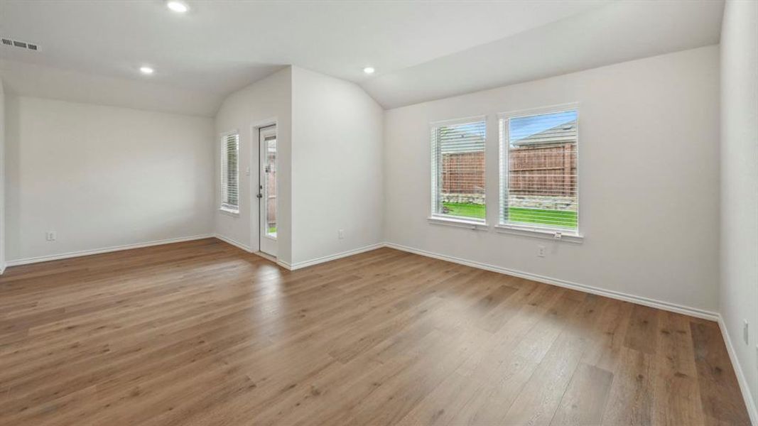 Spacious room featuring wood-finish flooring and white walls