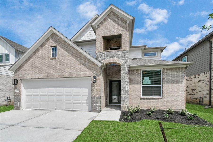 Meticulously maintained yard and lush landscape, paired with a premium elevation featuring captivating brick and stone accents. Modern coach lights add a touch of contemporary elegance to the exterior. Sample photo of completed home with similar plan. As built color and selections may vary.