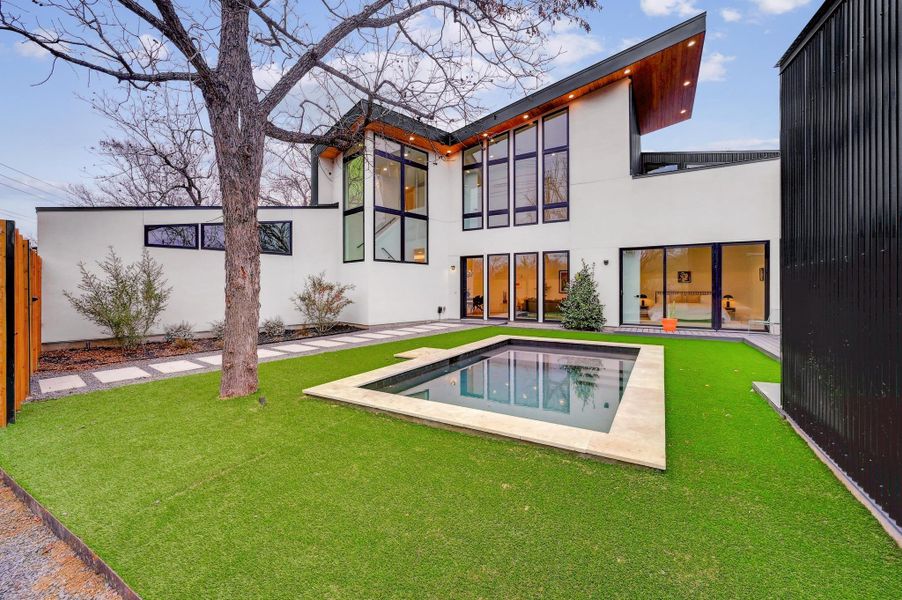 Rear view of house with stucco siding, an outdoor pool, and a patio