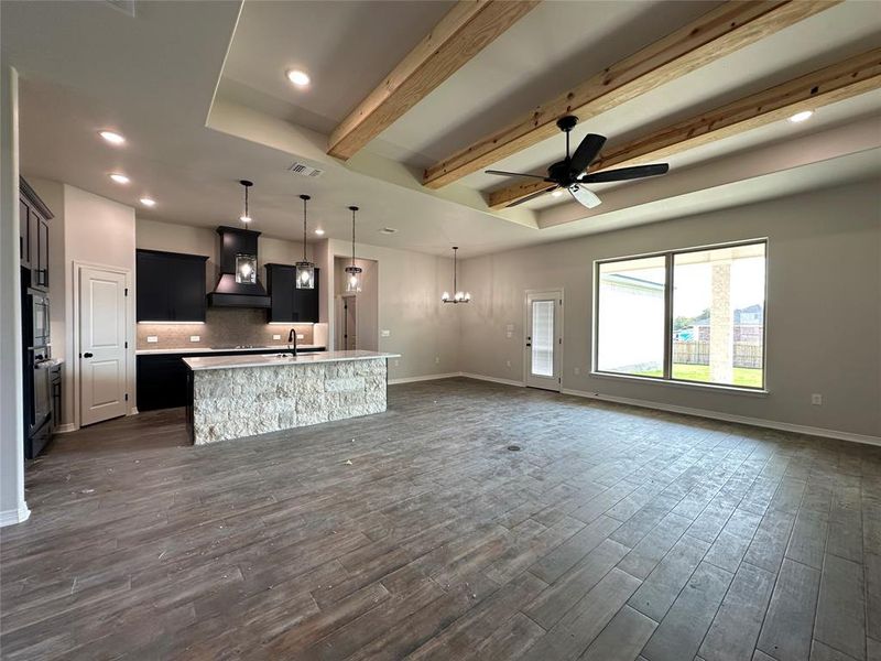 Kitchen with a chandelier, dark cabinetry, beam ceiling, decorative light fixtures, and custom range hood Kitchen with a chandelier, dark cabinetry, beam ceiling, decorative light fixtures, and custom range hood