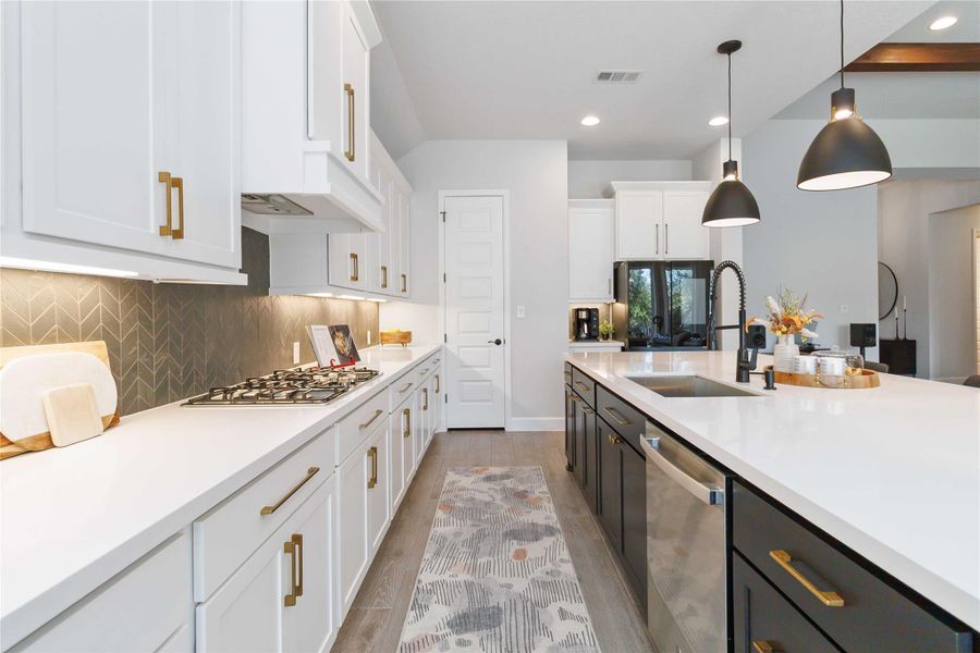 Kitchen with pendant lighting, light wood finished floors, decorative backsplash, white cabinets, and stainless steel appliances Kitchen with pendant lighting, light wood finished floors, decorative backsplash, white cabinets, and stainless steel appliances