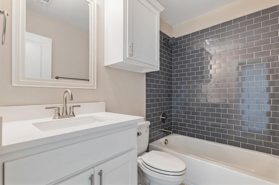 Full bathroom featuring tiled shower / bath combo, toilet, and vanity Full bathroom featuring tiled shower / bath combo, toilet, and vanity