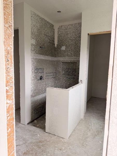 Framed shower enclosure with integrated shelving niche, featuring water-resistant wall backing and a ceiling-mounted light fixture
