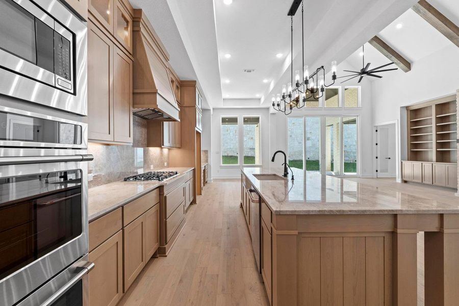 Kitchen with beamed ceiling, light stone countertops, stainless steel appliances, backsplash, and light wood-type flooring Kitchen with beamed ceiling, light stone countertops, stainless steel appliances, backsplash, and light wood-type flooring