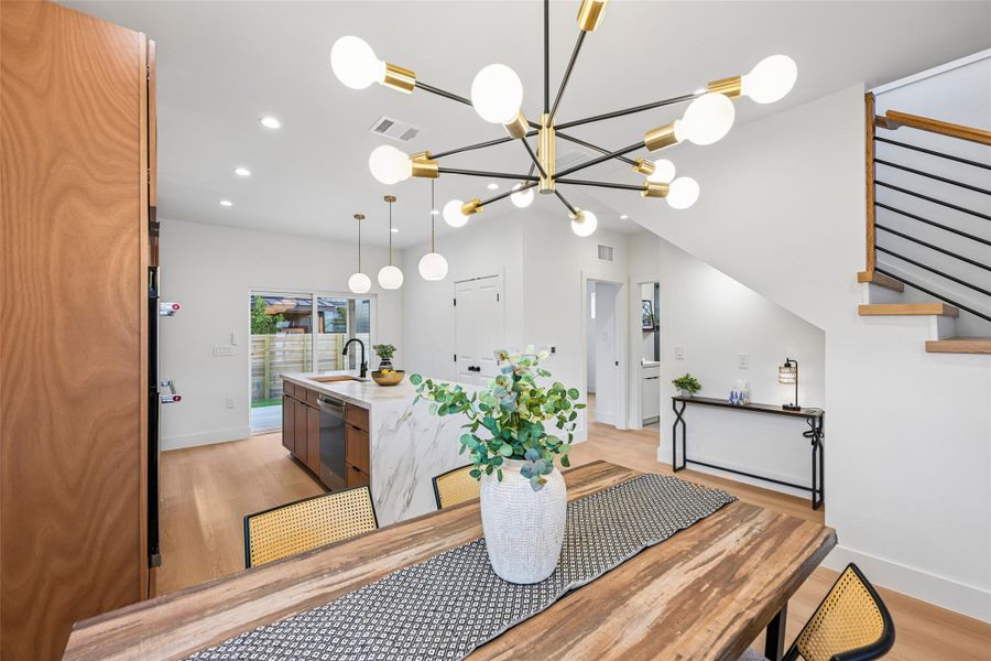 Modern design elements unite this open concept living space, from the light wood flooring to the aesthetic chandelier.