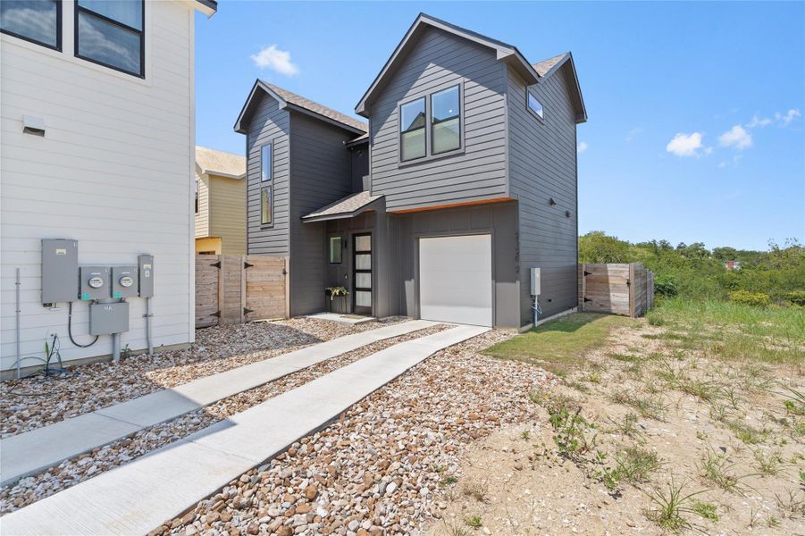 A contemporary charcoal grey residence boasts clean lines and an integrated garage, bordered by a simple gravel and concrete driveway. A contemporary charcoal grey residence boasts clean lines and an integrated garage, bordered by a simple gravel and concrete driveway.