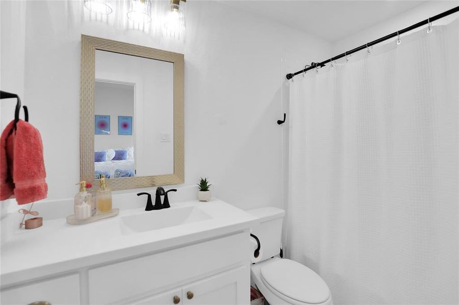 Bathroom featuring a white vanity with integrated sink, black faucet, and a rectangular mirror with a textured frame
