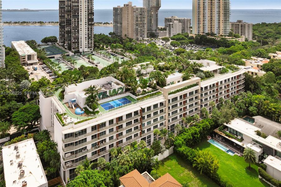 Multi-story residential complex featuring a rooftop sports court, integrated running track, and landscaped terrace greenery Multi-story residential complex featuring a rooftop sports court, integrated running track, and landscaped terrace greenery