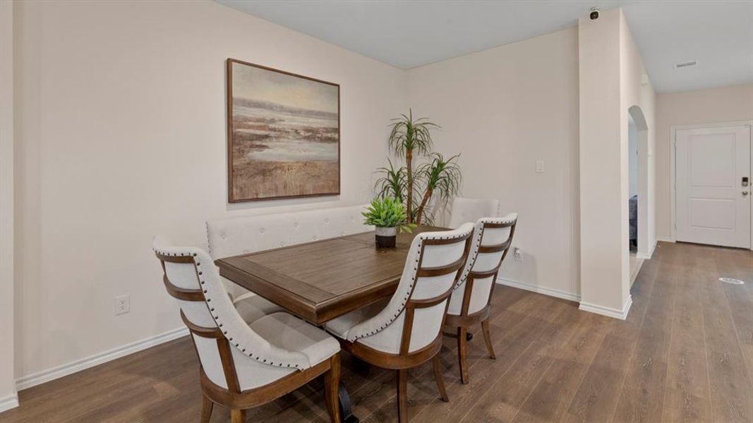 Dining space with arched walkways and dark wood finished floors