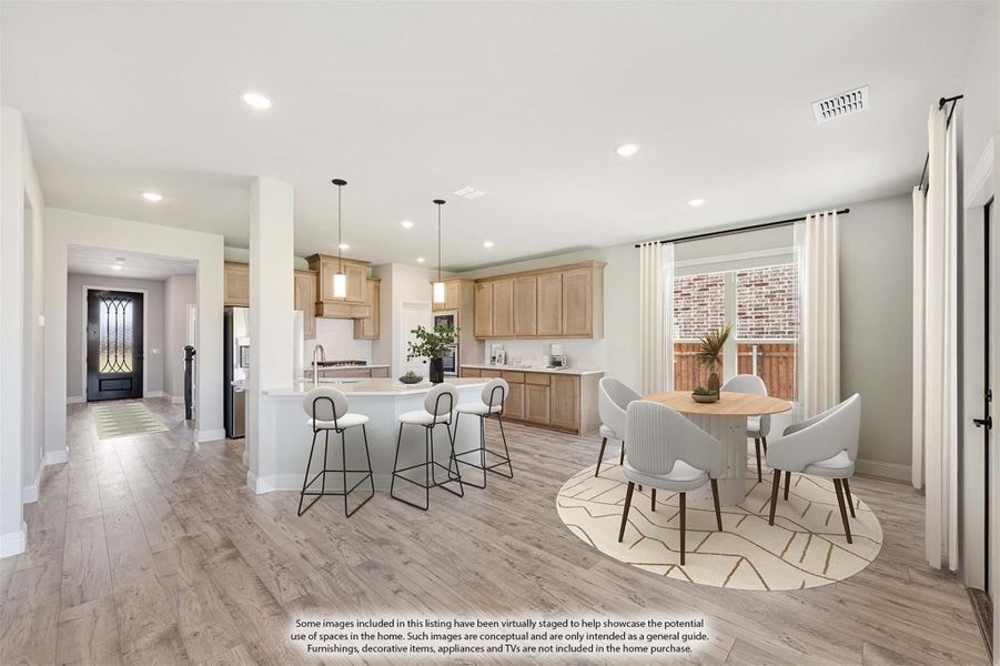 Open-plan kitchen and dining area with island, bar stools, light wood cabinets, and hardwood floors