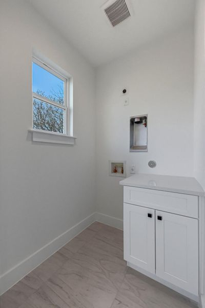 Laundry room featuring light marble finish floors, washer hookup, and cabinet space