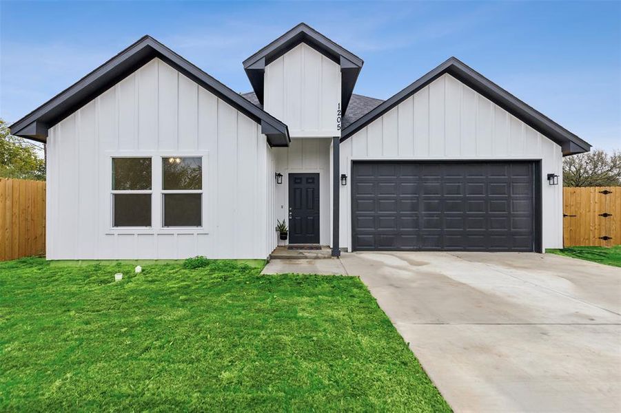 Modern inspired farmhouse featuring a garage and a front yard