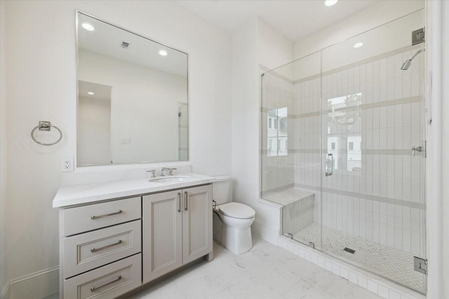 En-suite bathroom features a sleek, glass-encased shower, Quartz counters and additional counter and storage space.
