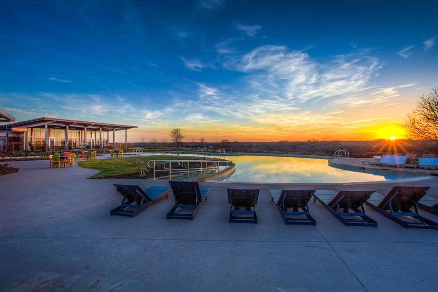 Pool at dusk featuring a patio area and a water view