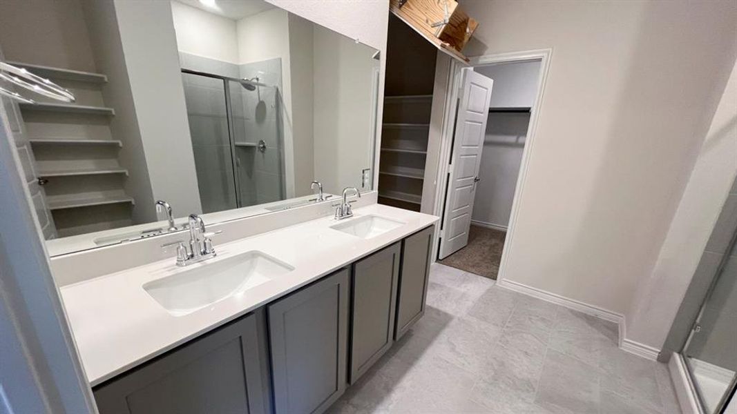 Full bathroom with a spacious closet, a stall shower, and double vanity