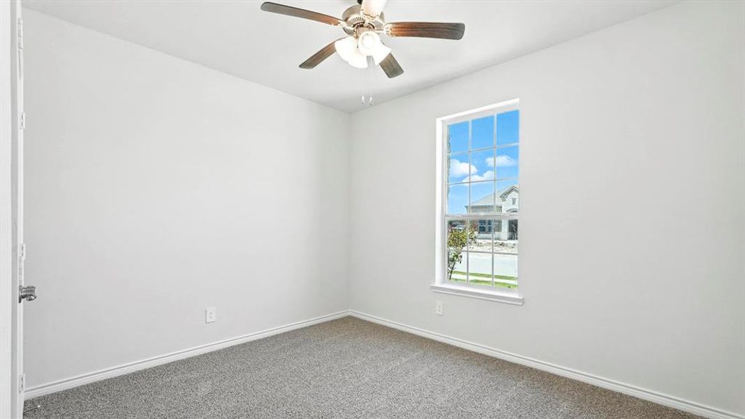 Room featuring a ceiling fan with light fixture, single window with grid pattern, neutral gray carpeting, white baseboards, and white painted walls Room featuring a ceiling fan with light fixture, single window with grid pattern, neutral gray carpeting, white baseboards, and white painted walls