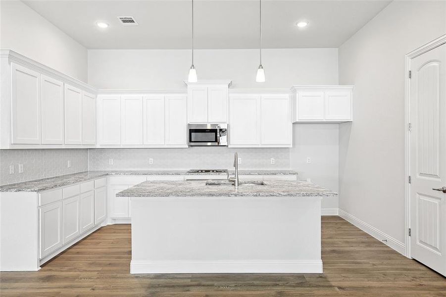 Kitchen with white cabinets, light stone counters, tasteful backsplash, and recessed lighting