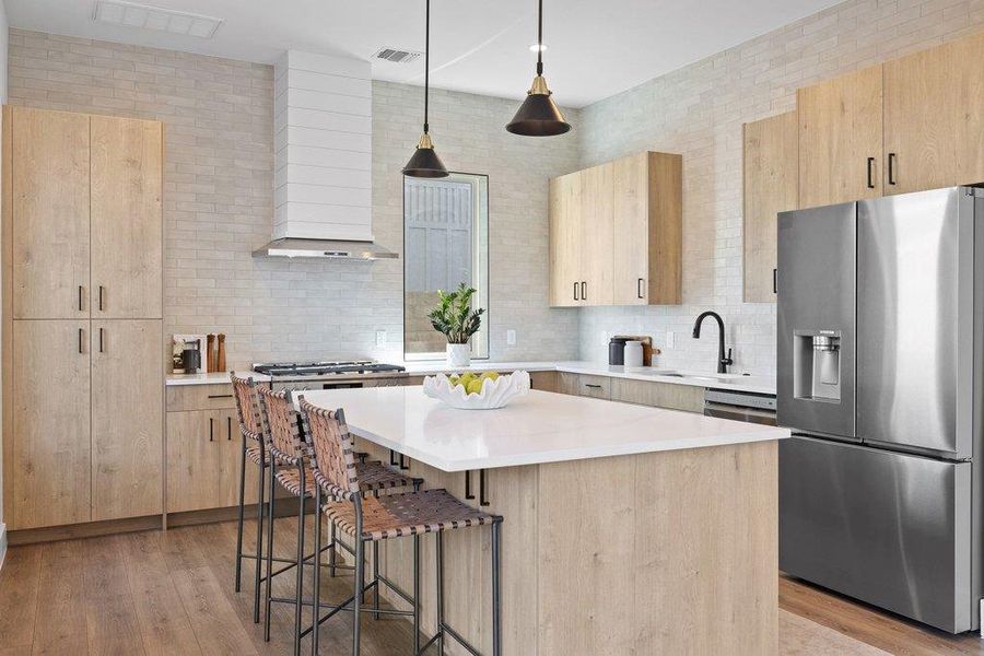 Kitchen with wood grain finished cabinets, stainless steel refrigerator with dual ice / party ice dispenser, a center island with microwave and plenty of extra storage, and upgrade 36” gas range