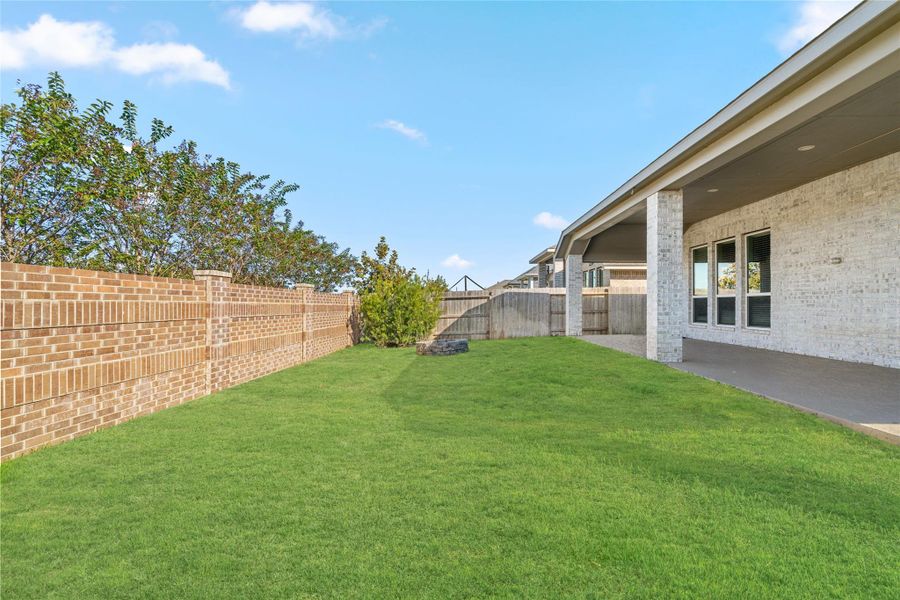 View showing the ample yard space, full fencing, and landscaping potential.