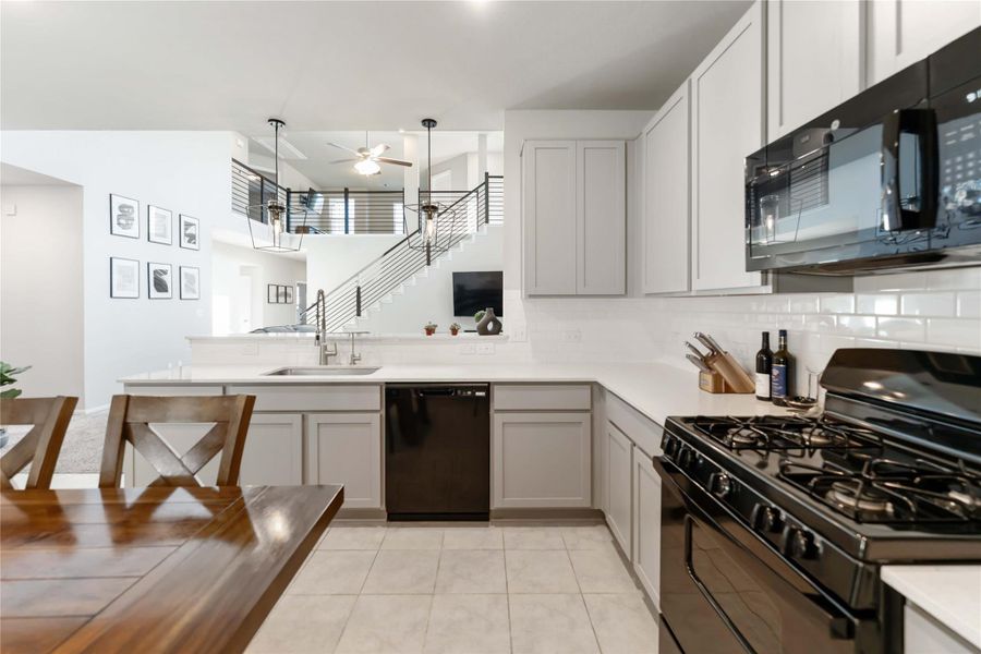 Black appliances, gas range, and elegant tile backsplash create a clean, modern look that complements the home’s open-concept design. Black appliances, gas range, and elegant tile backsplash create a clean, modern look that complements the home’s open-concept design.
