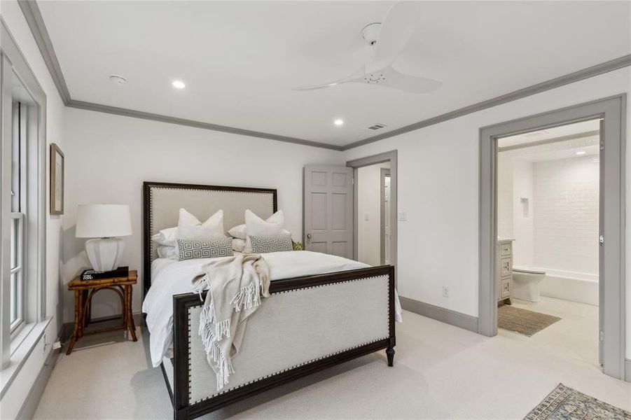 Bedroom featuring ceiling fan, light colored carpet, visible vents, baseboards, and crown molding