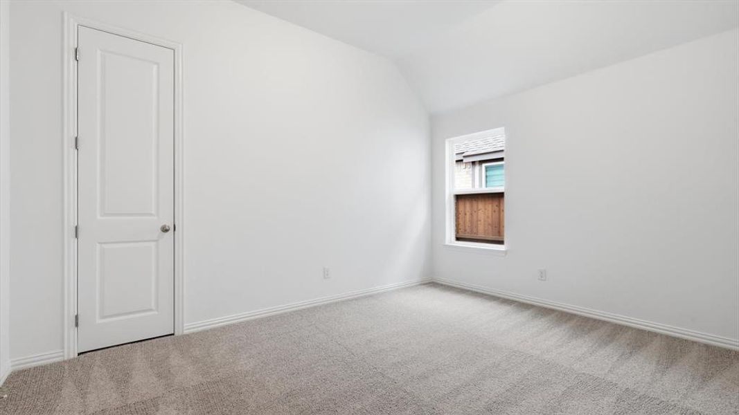 Spacious room featuring vaulted ceilings, a neutral color palette, and light gray carpet flooring Spacious room featuring vaulted ceilings, a neutral color palette, and light gray carpet flooring