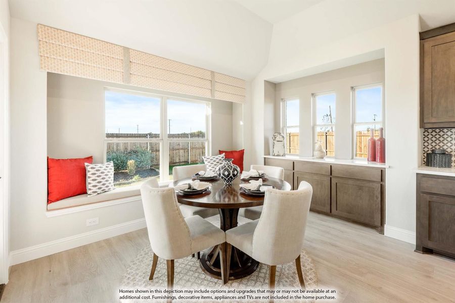 Bright dining nook with round table, window seat with red pillows, and light hardwood floors Bright dining nook with round table, window seat with red pillows, and light hardwood floors