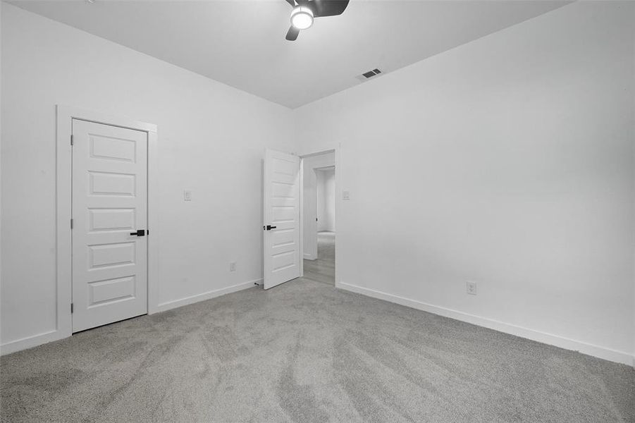 Unfurnished bedroom featuring light carpet and a ceiling fan Unfurnished bedroom featuring light carpet and a ceiling fan