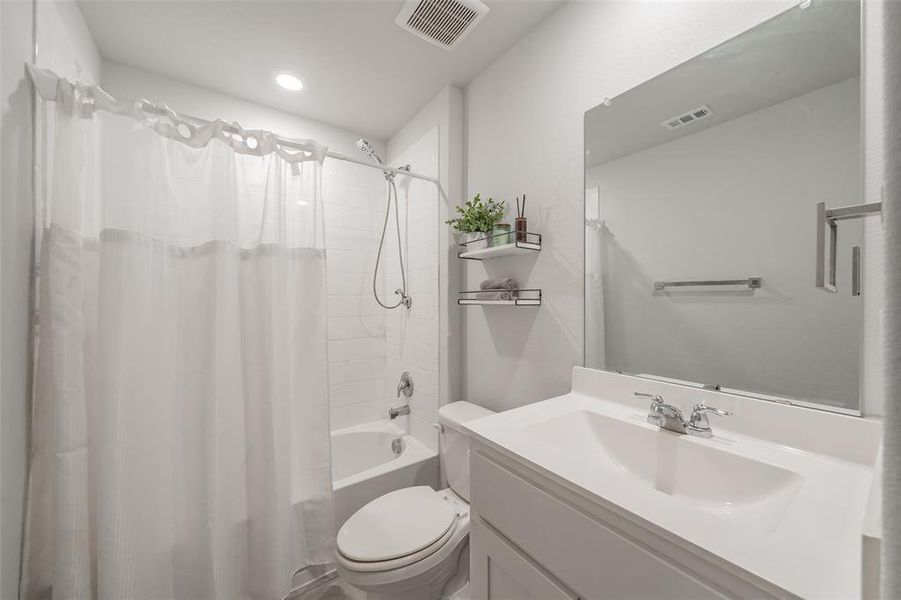 Full bathroom featuring a single vanity with an integrated sink, a rectangular mirror, a shower-over-tub combination with white subway tile surround, and a toilet