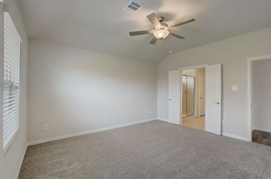 Unfurnished bedroom featuring light carpet, vaulted ceiling, and ceiling fan