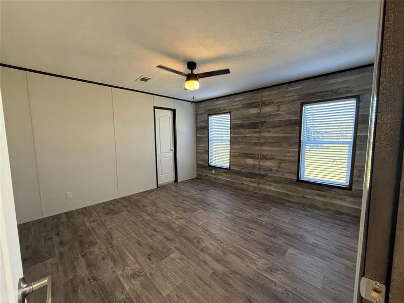Unfurnished bedroom with a textured ceiling, dark wood-style flooring, a ceiling fan, and a closet