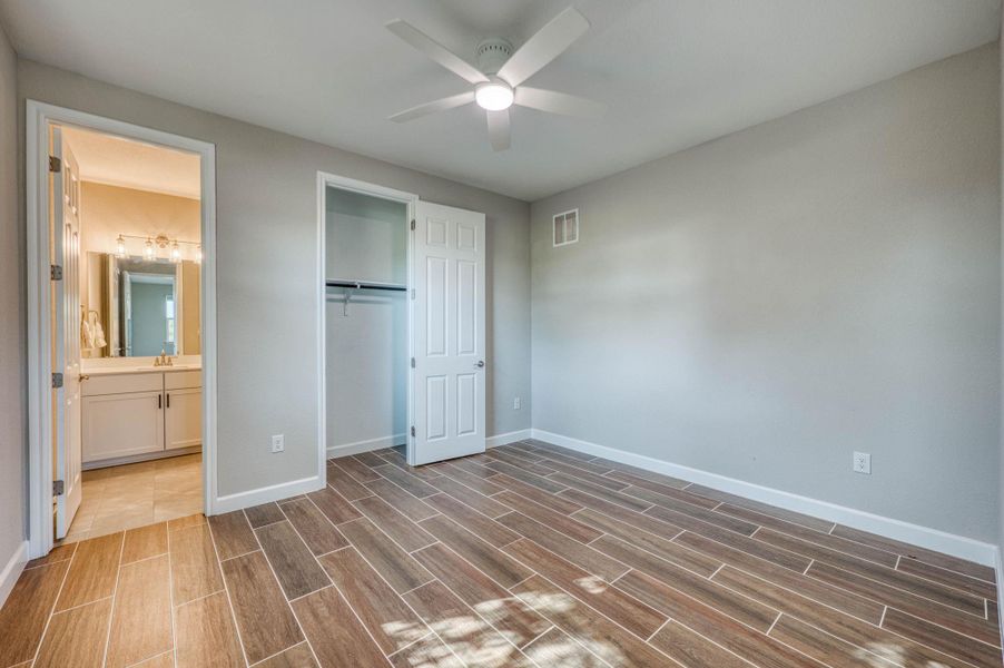 Gleaming wood-look tile flooring runs throughout this serene bedroom featuring a private walk-in closet. Gleaming wood-look tile flooring runs throughout this serene bedroom featuring a private walk-in closet.