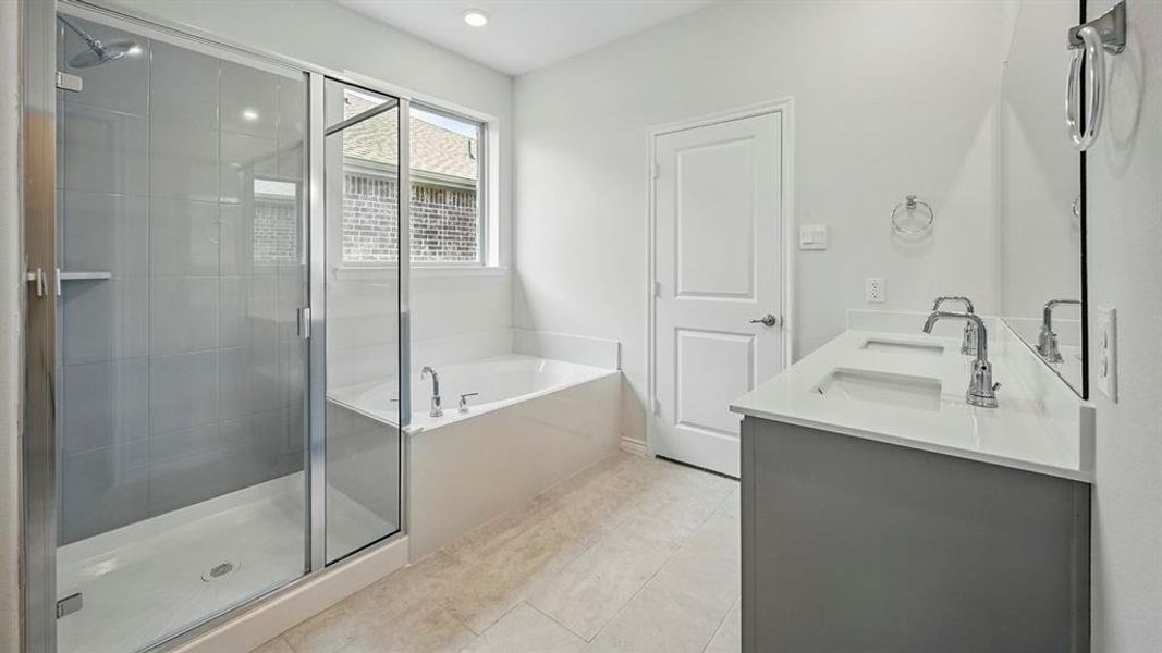 Full bathroom with double vanity, a shower stall, a garden tub, and light tile patterned floors