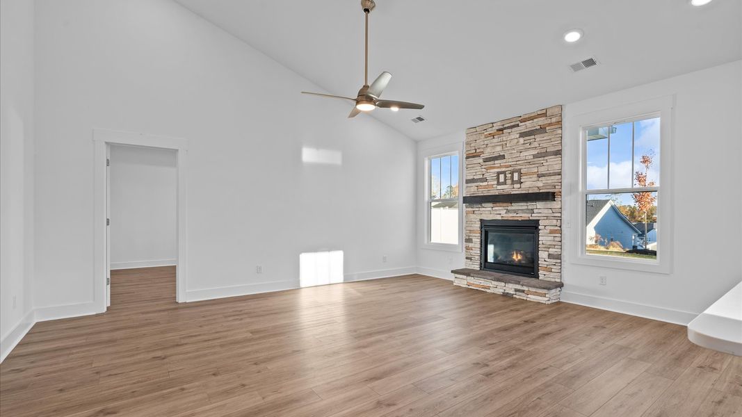 Eye-catching two-story family room with elegant trim, oversized windows, stone fireplace, and elevated design