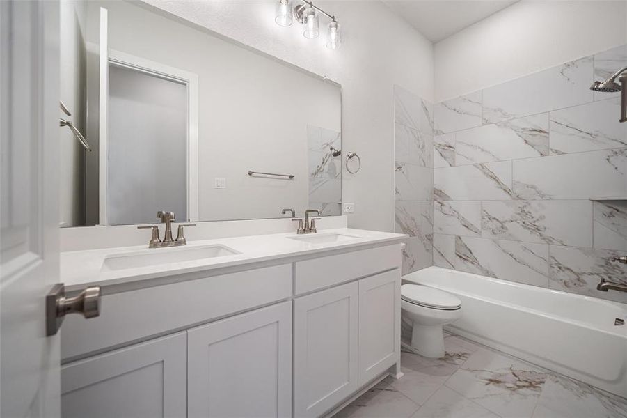 Bathroom with light marble finish floors, double vanity, and shower / bath combination Bathroom with light marble finish floors, double vanity, and shower / bath combination