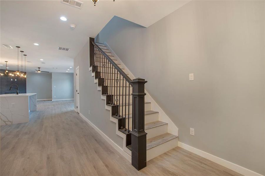 Staircase featuring wood-type flooring and sink