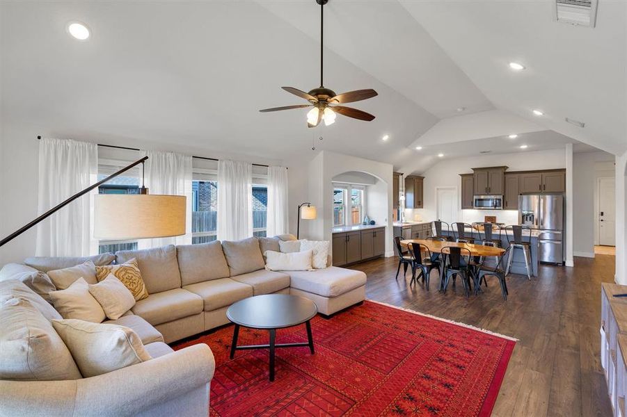 Living room with ceiling fan, dark hardwood / wood-style flooring, and vaulted ceiling