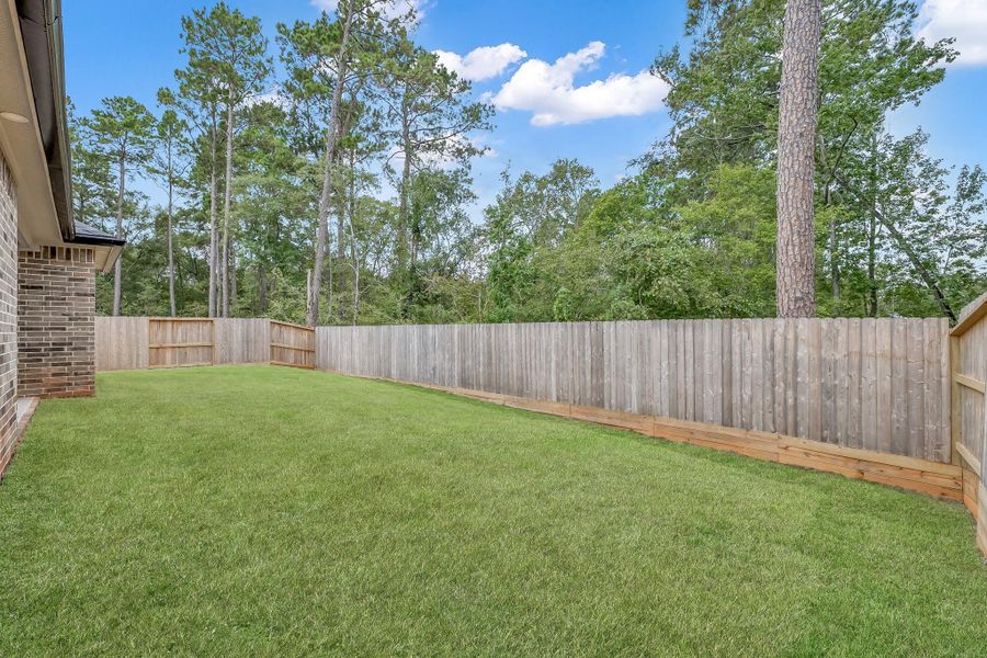 Spacious backyard with a well-maintained lawn, bordered by a wooden fence, offering privacy and a natural view of tall trees. Ideal for outdoor activities. Spacious backyard with a well-maintained lawn, bordered by a wooden fence, offering privacy and a natural view of tall trees. Ideal for outdoor activities.