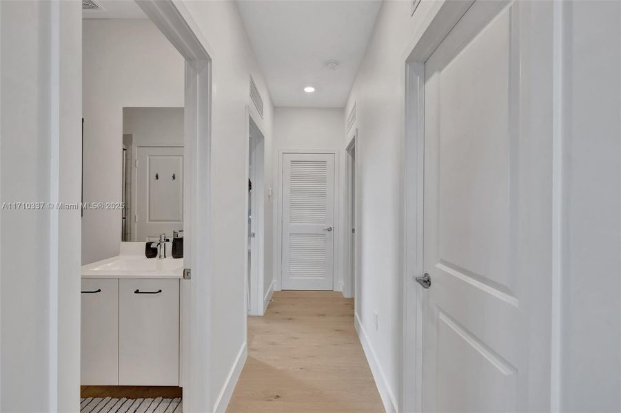 bathroom (also accessible to bedroom through another door). Laundry room to right, and two bedrooms at the end of hall (with AC handler closet in between)