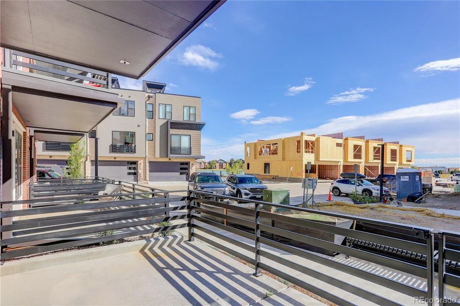 Partially covered front patio sits on grassy courtyard, across from path to lake