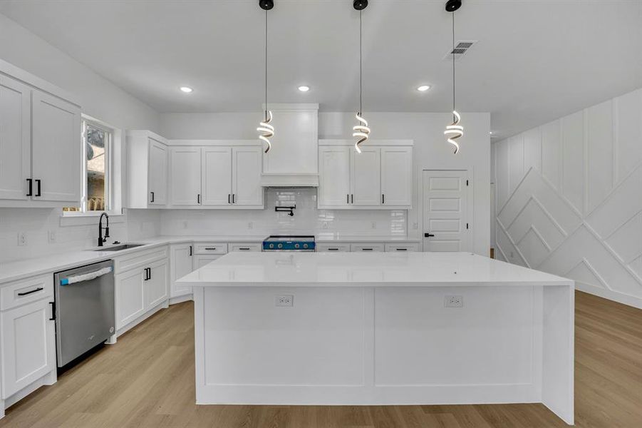 Kitchen with premium range hood, a kitchen island, appliances with stainless steel finishes, pendant lighting, and sink