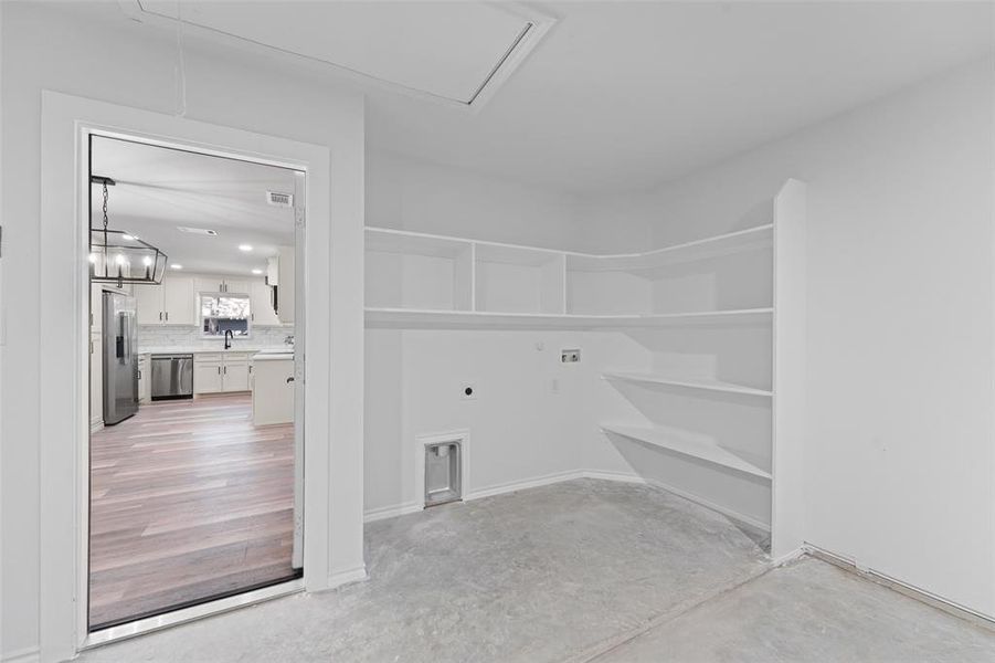 Utility room with concrete flooring, built-in shelving, and laundry hookups Utility room with concrete flooring, built-in shelving, and laundry hookups
