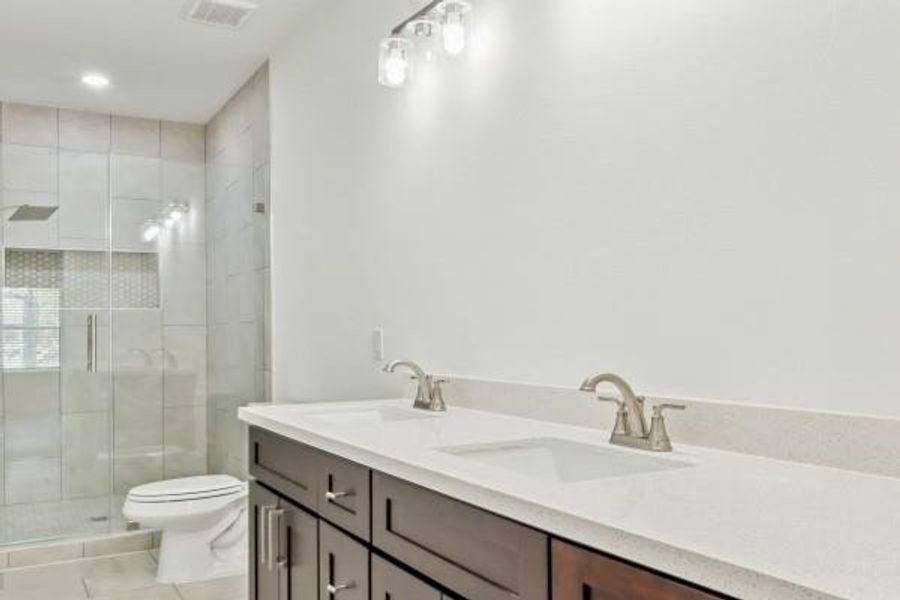 Experience luxury in this elegant primary bathroom, featuring a spacious double vanity and a sleek, glass-enclosed shower. Experience luxury in this elegant primary bathroom, featuring a spacious double vanity and a sleek, glass-enclosed shower.